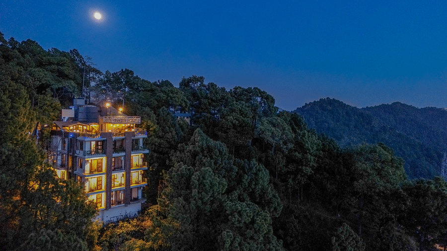 A drone shot of DLS Whispering Winds surrounded by tress, mountains and lush greenery
